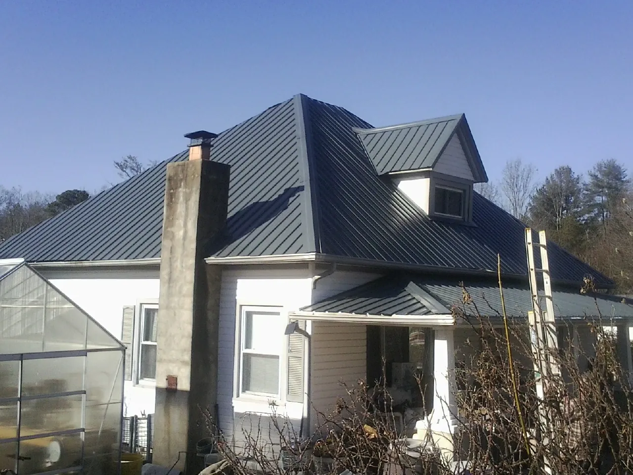 Dark blue standing seam metal roof on a white farmhouse with dormer — Slate & Tile Roof Repair by Roofing Brothers in Ligonier