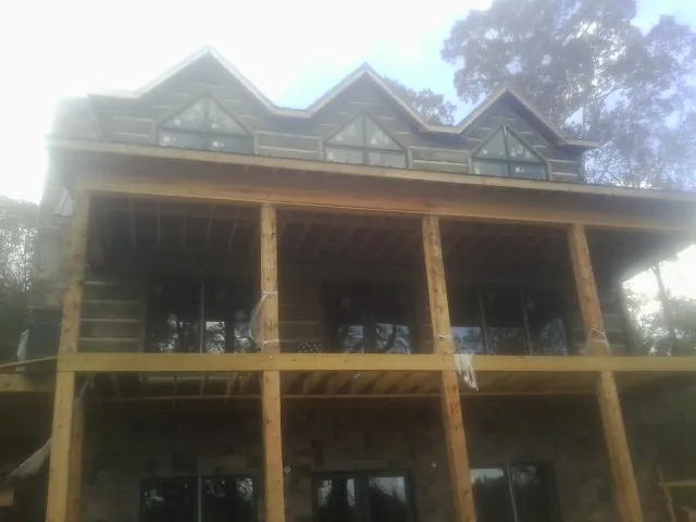 Dormers and porch framing on a large log home under construction — Roof Coating work by our crew in Ligonier