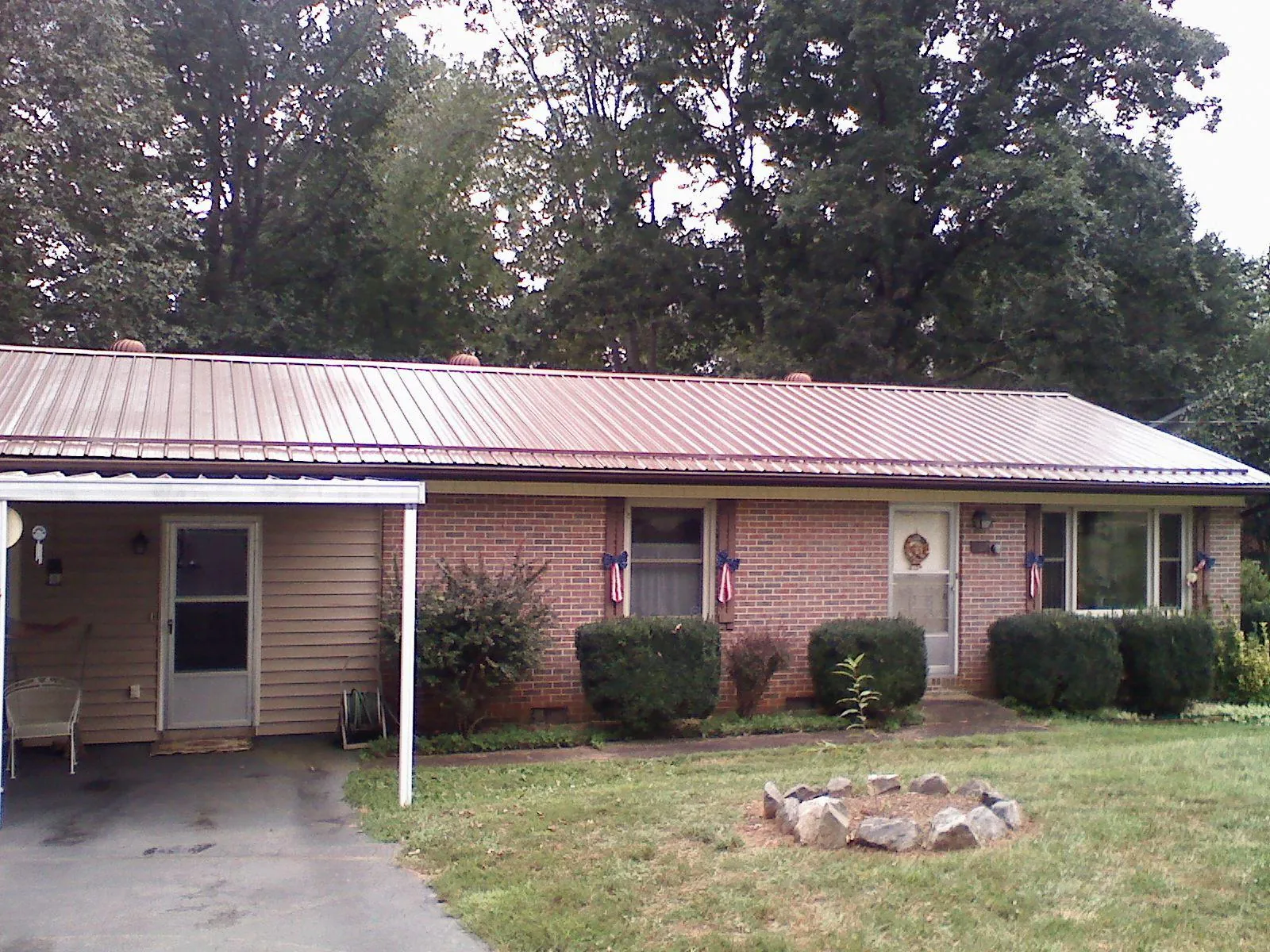 Bronze metal roof and carport on a brick ranch home — Roof Repair work by our crew in Ligonier