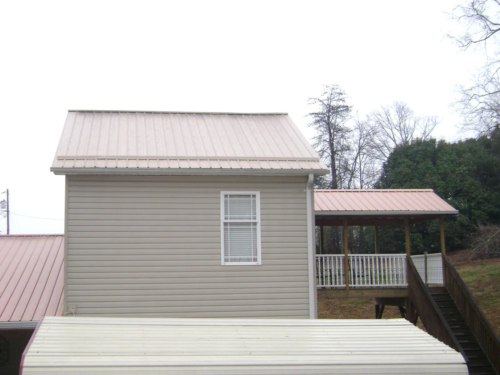 Tan metal roofs on a two story addition and attached porch, from a Roof Replacement job in Ligonier