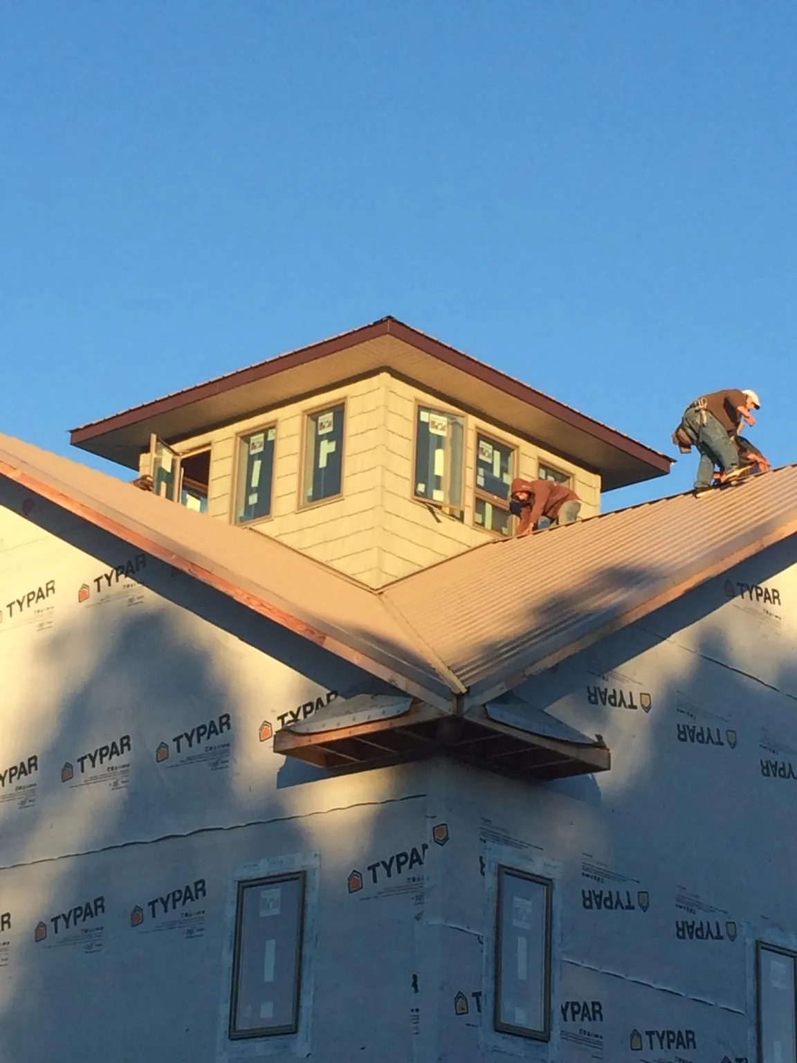 Roofers working around a rooftop cupola on a new metal roof at sunset — Roof Waterproofing in Ligonier by Roofing Brothers